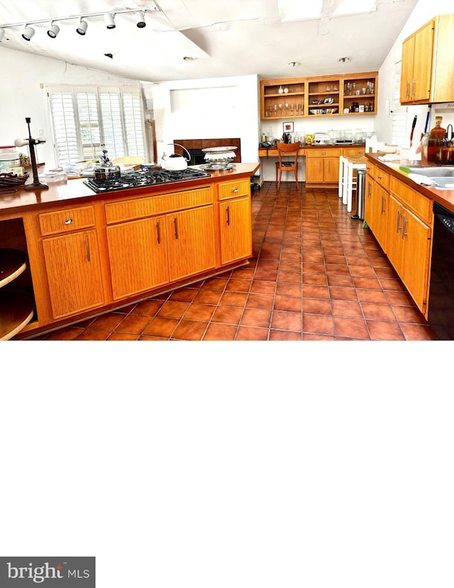 kitchen with lofted ceiling, dark tile patterned floors, dishwasher, gas cooktop, and sink