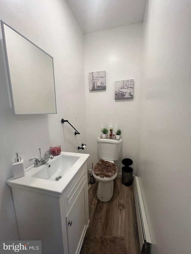 bathroom featuring hardwood / wood-style floors, baseboard heating, vanity, and toilet