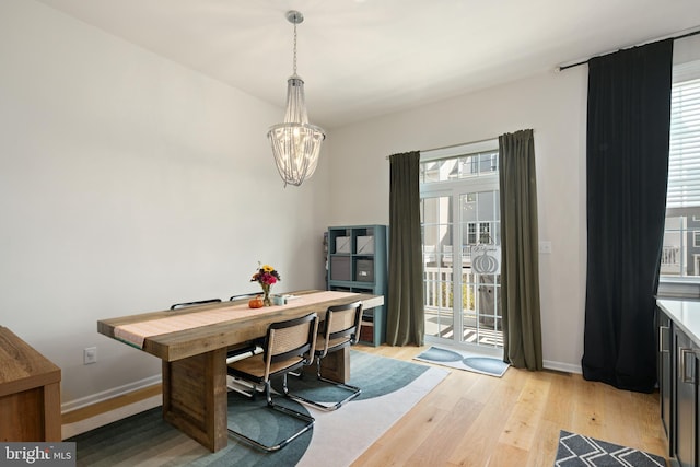 dining area with light wood-type flooring, a chandelier, and plenty of natural light