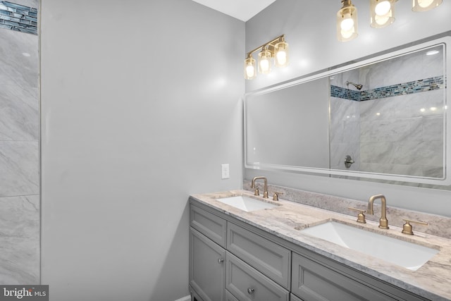 full bathroom featuring double vanity, tiled shower, and a sink