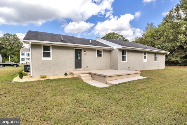 rear view of property featuring a yard and stucco siding