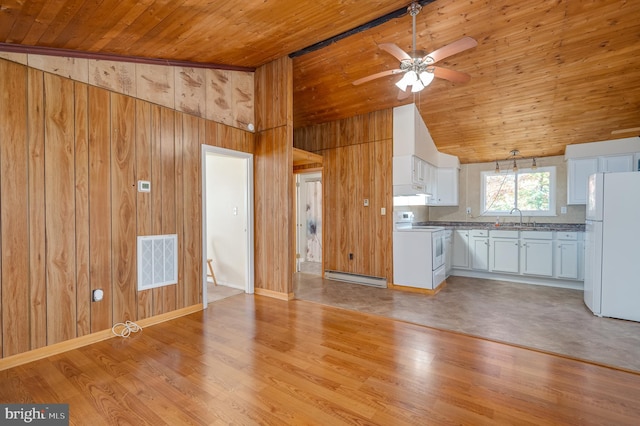 kitchen with baseboard heating, white appliances, white cabinetry, light hardwood / wood-style floors, and wood walls