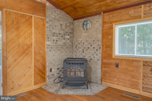 interior details with a wood stove, hardwood / wood-style floors, and wooden walls