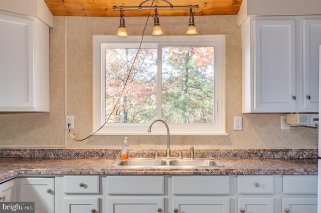 kitchen with sink, white cabinetry, and decorative light fixtures