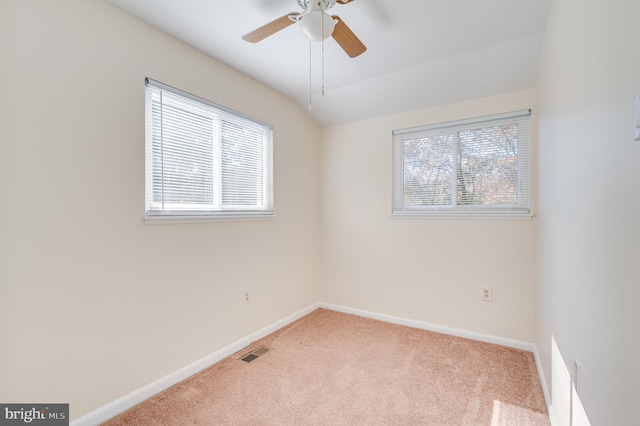 carpeted empty room with a wealth of natural light, vaulted ceiling, and ceiling fan