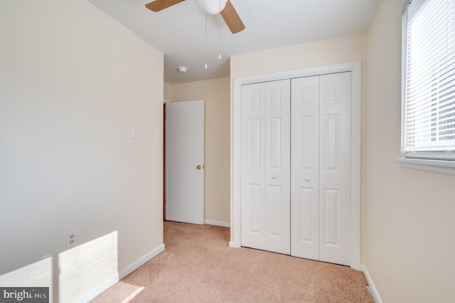 unfurnished bedroom featuring light carpet, multiple windows, a closet, and ceiling fan