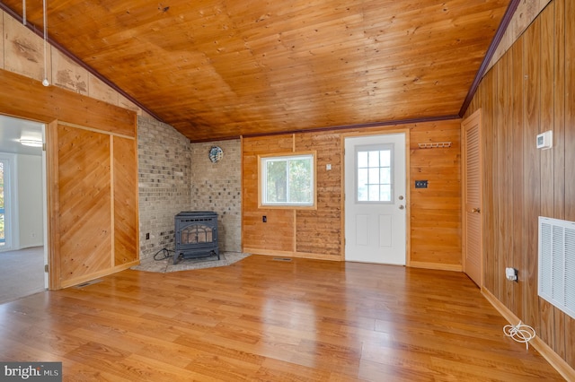 unfurnished living room featuring hardwood / wood-style floors, vaulted ceiling, a wood stove, and wooden ceiling