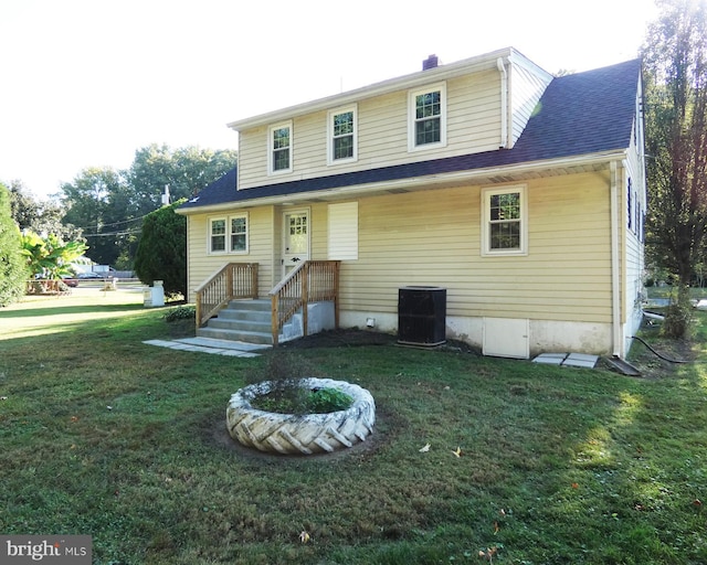 rear view of house featuring central air condition unit and a lawn