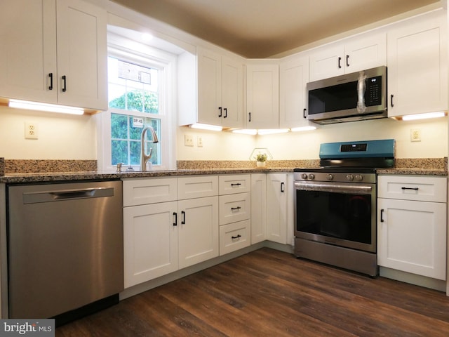 kitchen with dark wood-type flooring, stainless steel appliances, and white cabinets