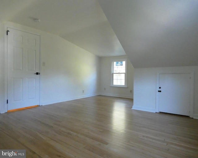 additional living space featuring light hardwood / wood-style floors and vaulted ceiling