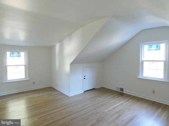 bonus room with lofted ceiling, light hardwood / wood-style flooring, and a healthy amount of sunlight