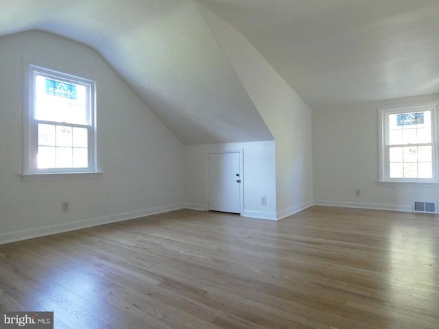 additional living space with plenty of natural light, lofted ceiling, and light wood-type flooring