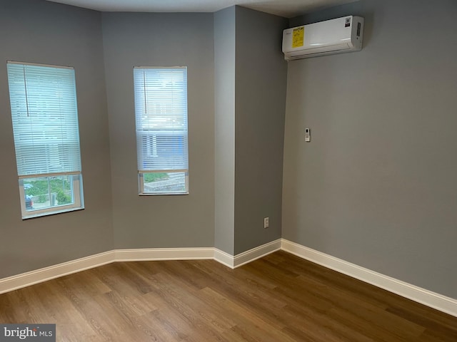 empty room featuring hardwood / wood-style flooring, plenty of natural light, and a wall mounted AC