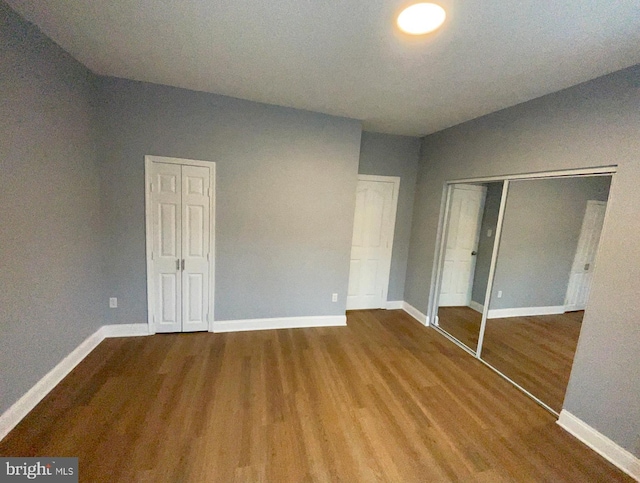 unfurnished bedroom with hardwood / wood-style flooring and lofted ceiling