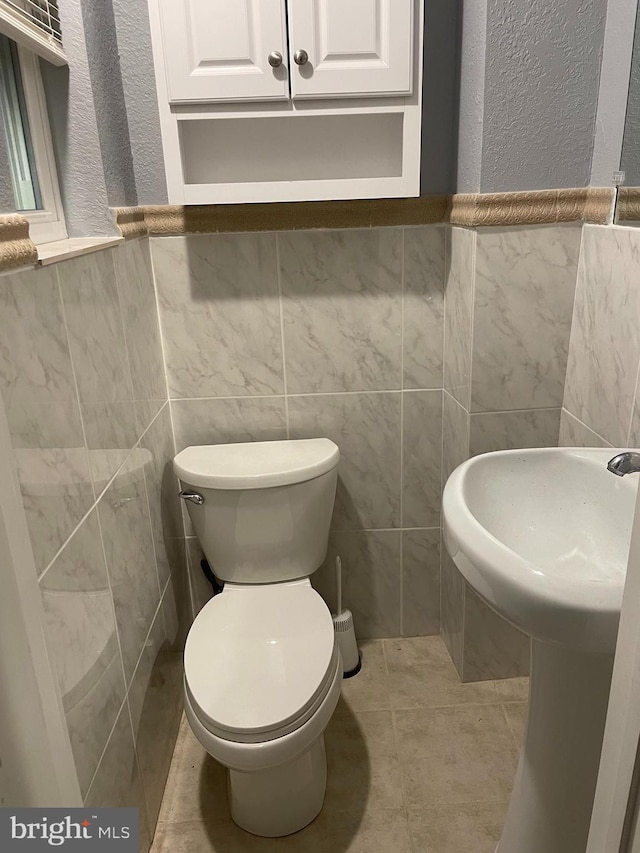 bathroom featuring tile walls, tile patterned flooring, and toilet