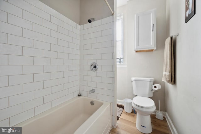 bathroom with tiled shower / bath combo, hardwood / wood-style floors, toilet, and a healthy amount of sunlight