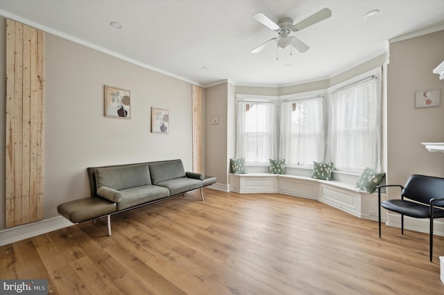 sitting room with light wood-type flooring, ceiling fan, and crown molding