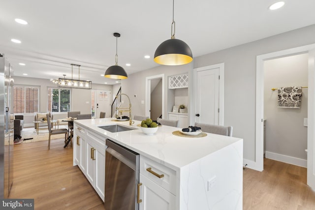 kitchen with white cabinets, an island with sink, sink, decorative light fixtures, and dishwasher