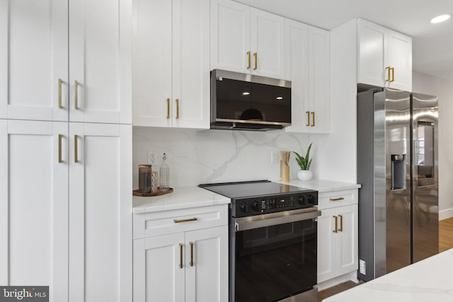 kitchen featuring appliances with stainless steel finishes, light stone counters, tasteful backsplash, white cabinets, and hardwood / wood-style floors