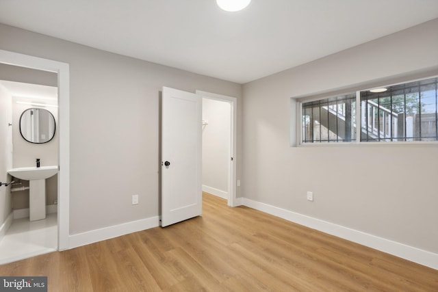 unfurnished bedroom with light wood-type flooring, ensuite bath, and sink