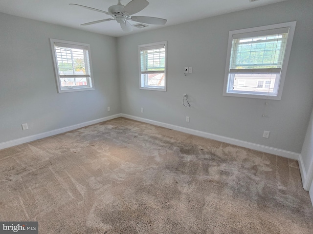 empty room with a wealth of natural light, ceiling fan, and light colored carpet