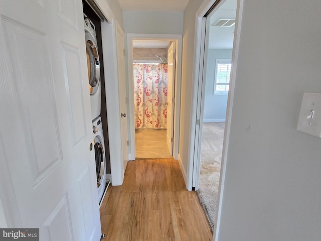 corridor featuring stacked washer / dryer and light wood-type flooring