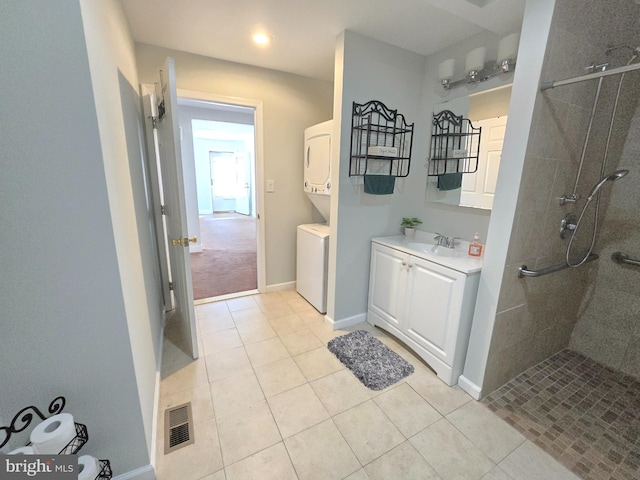 bathroom with tiled shower, stacked washer and dryer, vanity, and tile patterned floors