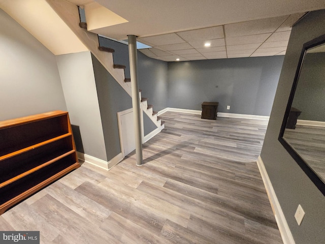 basement with a paneled ceiling and wood-type flooring