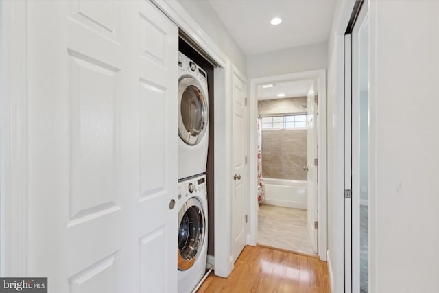 laundry room featuring stacked washer and clothes dryer and light wood-type flooring