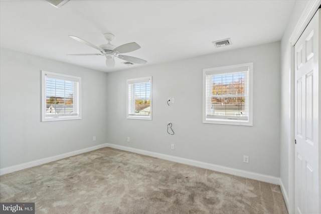 unfurnished bedroom with ceiling fan, multiple windows, and light carpet