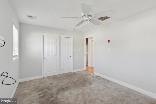 unfurnished bedroom featuring light colored carpet, ceiling fan, and a closet