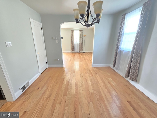 unfurnished dining area featuring a chandelier and light hardwood / wood-style flooring