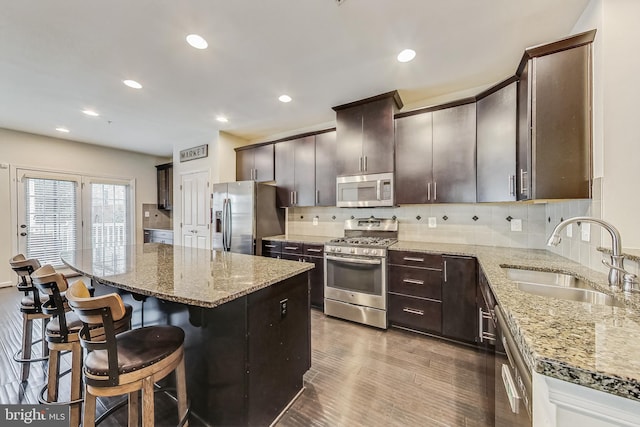 kitchen with light stone countertops, a center island, sink, and stainless steel appliances