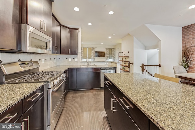 kitchen featuring appliances with stainless steel finishes, dark brown cabinets, sink, and light stone counters