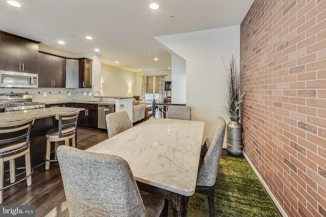 dining room with dark hardwood / wood-style flooring, sink, and brick wall