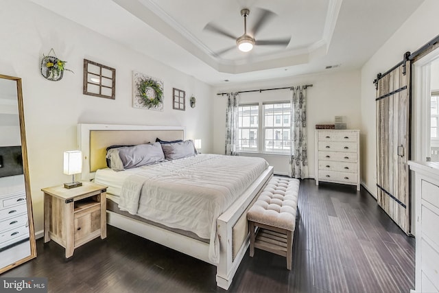 bedroom with a barn door, a raised ceiling, ceiling fan, and dark wood-type flooring