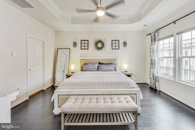 bedroom featuring ceiling fan, a raised ceiling, dark wood-type flooring, and crown molding