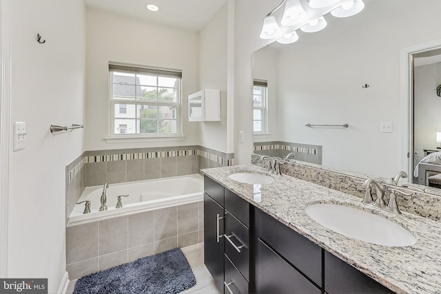 bathroom with tile patterned floors, tiled tub, and vanity