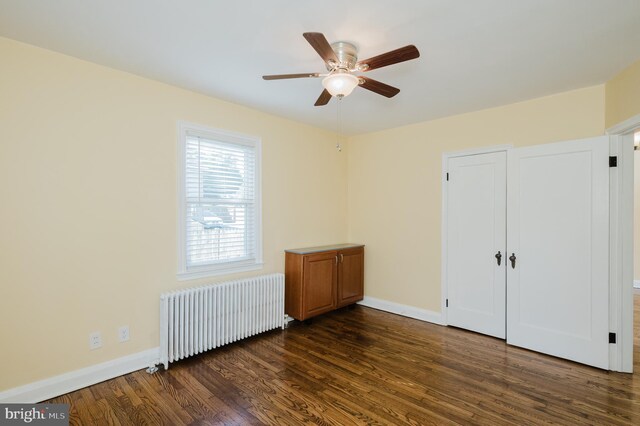 unfurnished bedroom featuring radiator heating unit, ceiling fan, and dark wood-type flooring