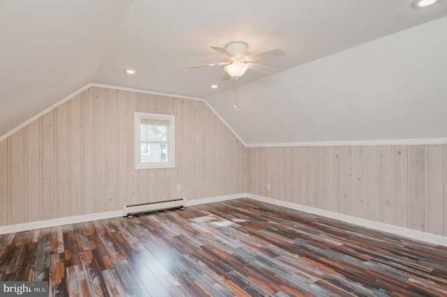 additional living space with wood walls, dark hardwood / wood-style flooring, lofted ceiling, ceiling fan, and a baseboard heating unit