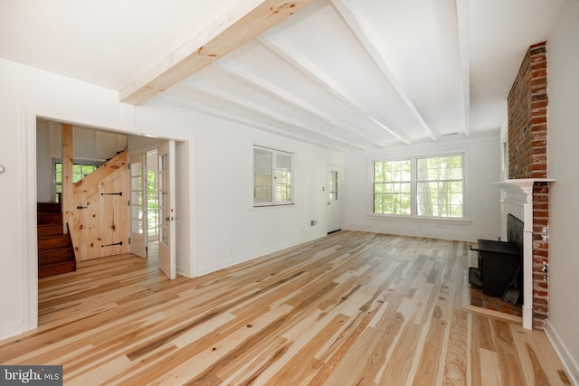 unfurnished living room featuring light wood-type flooring and beamed ceiling