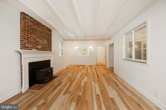 unfurnished living room featuring hardwood / wood-style flooring, beam ceiling, and a wood stove