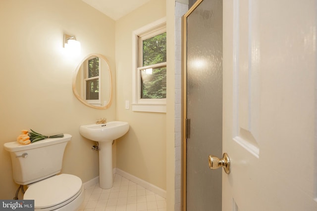 bathroom featuring sink, tile patterned flooring, a shower with door, and toilet