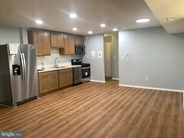 kitchen with appliances with stainless steel finishes, dark hardwood / wood-style floors, and sink