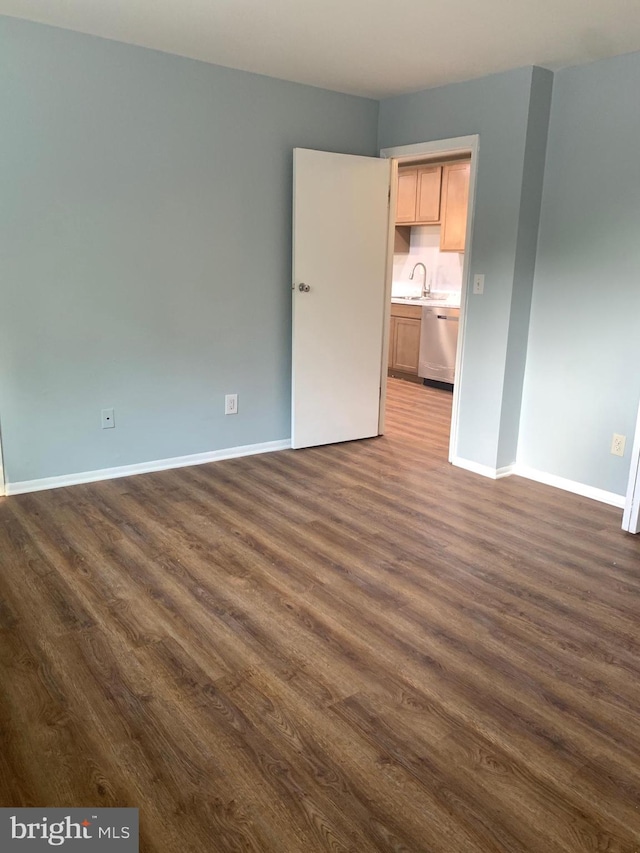 spare room with sink and dark wood-type flooring