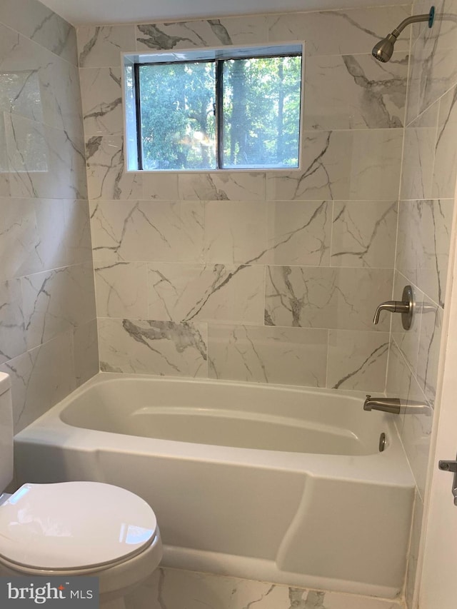 bathroom featuring tiled shower / bath combo and toilet