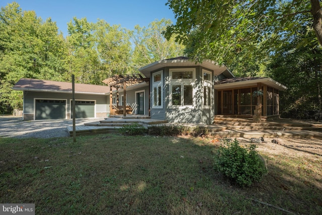 view of front of home featuring a sunroom, a front lawn, and a garage