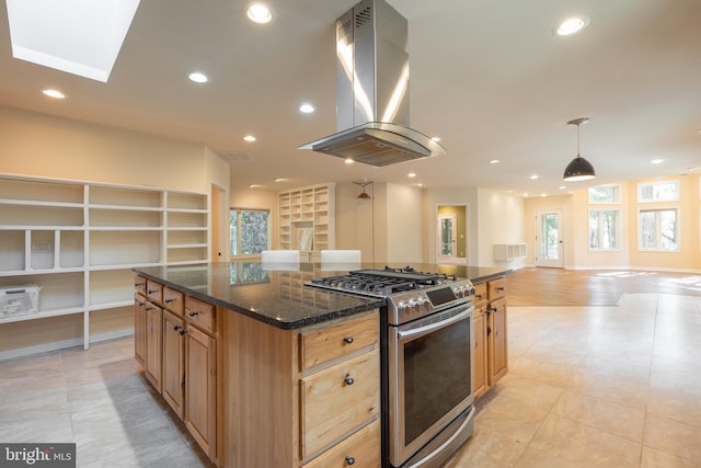 kitchen featuring pendant lighting, a kitchen island, stainless steel gas stove, range hood, and dark stone counters