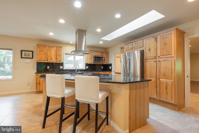 kitchen with a center island, island exhaust hood, stainless steel appliances, backsplash, and dark stone countertops