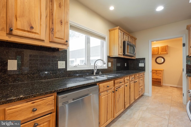 kitchen with dark stone counters, stainless steel appliances, tasteful backsplash, and sink